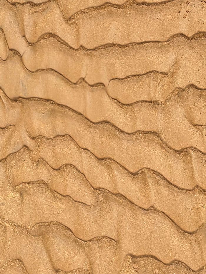 Close-up of rippled sand texture forming natural wavy patterns.
